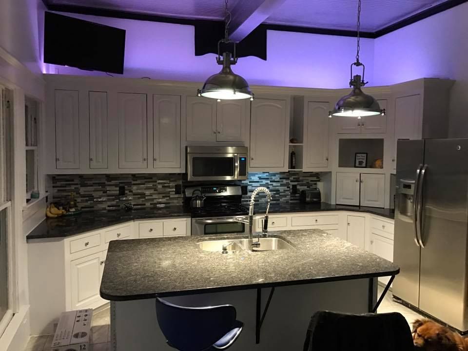 A kitchen with purple lights hanging from the ceiling