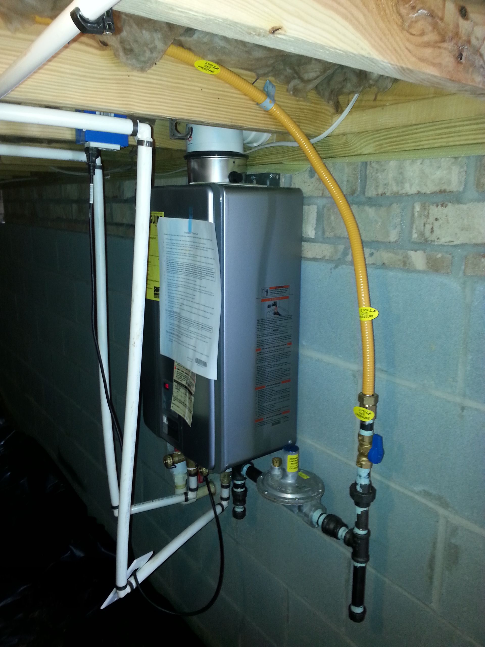A tankless water heater with a yellow hose attached to it.