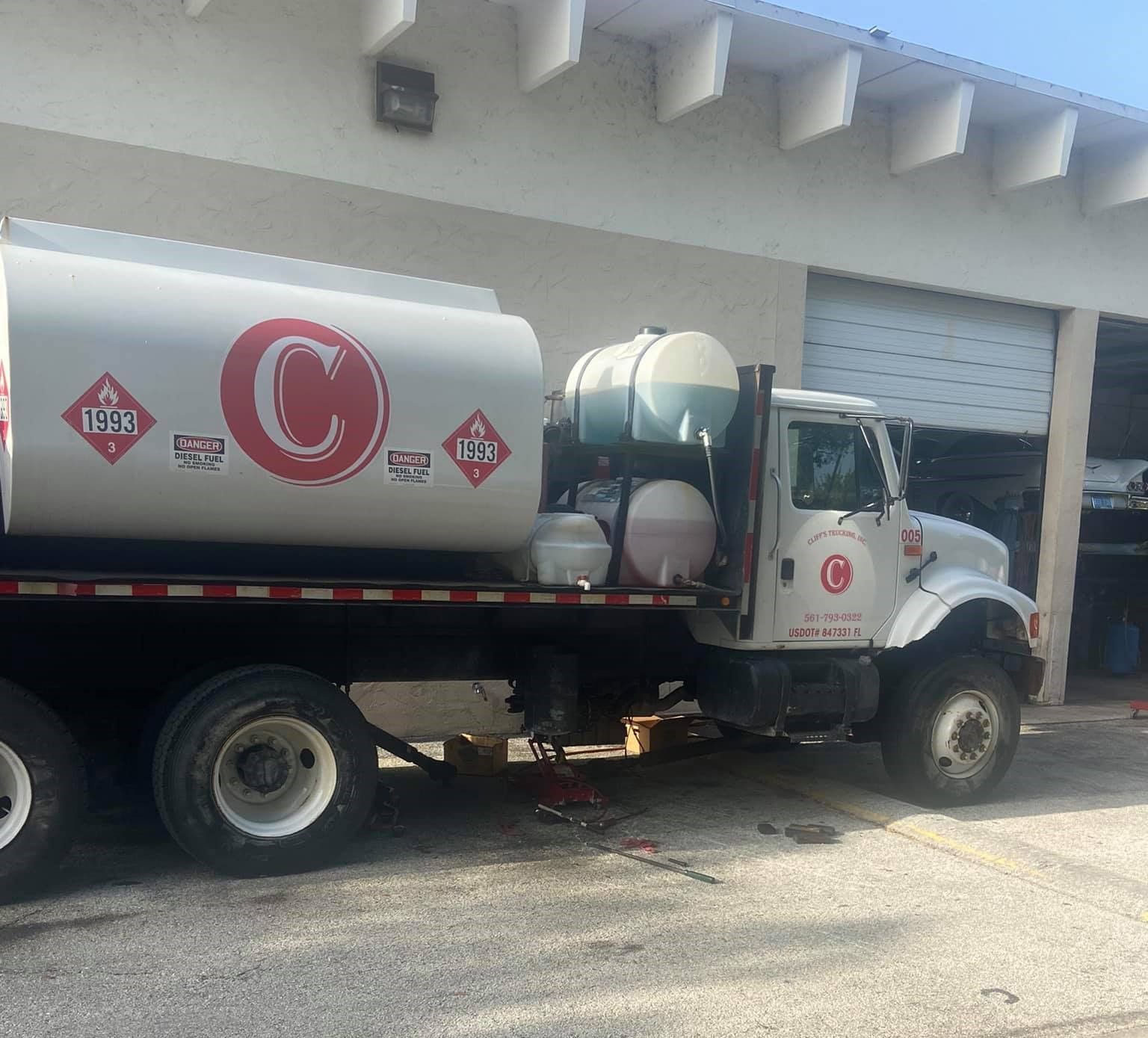 A white truck with the letter c on the side is parked in front of a building