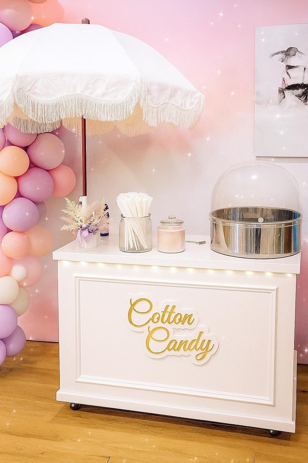 Cotton candy cart with white parasol and balloons, ready for a party.