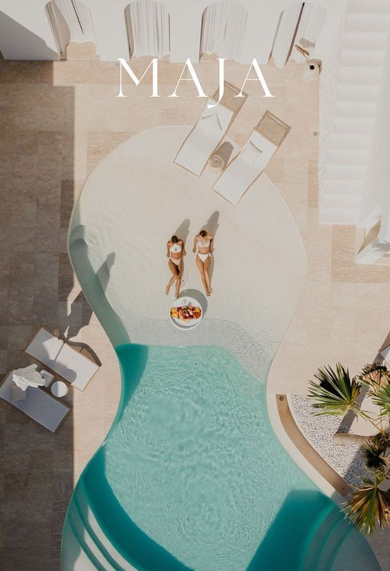 Aerial view of a pool with two people sunbathing, fruit plate. Bright, sunny day.