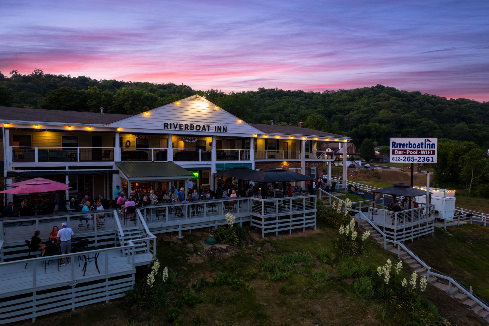 An aerial view of a hotel with people sitting on the deck at sunset.