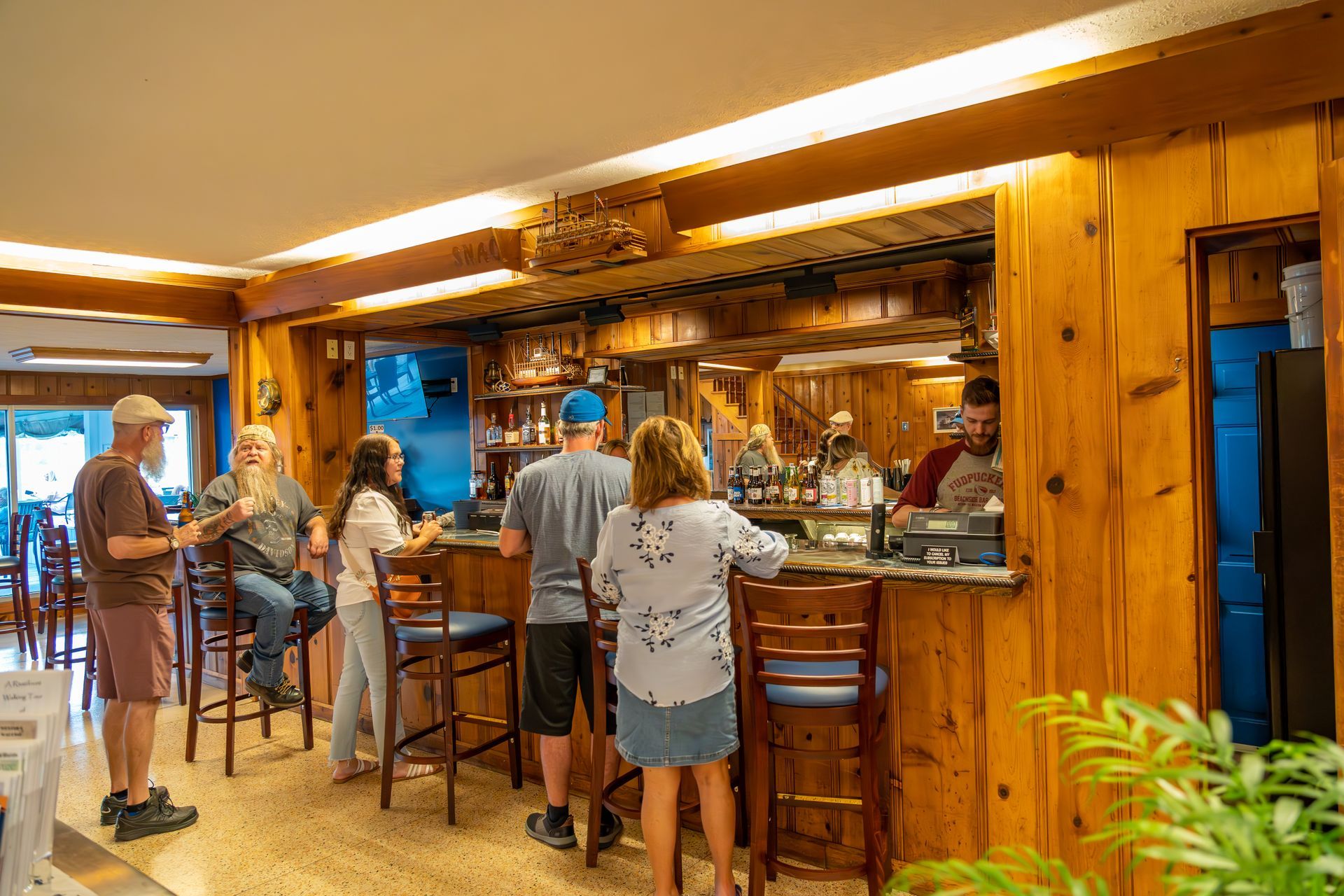 A group of people are sitting at a bar in Riverboat Inn lobby.