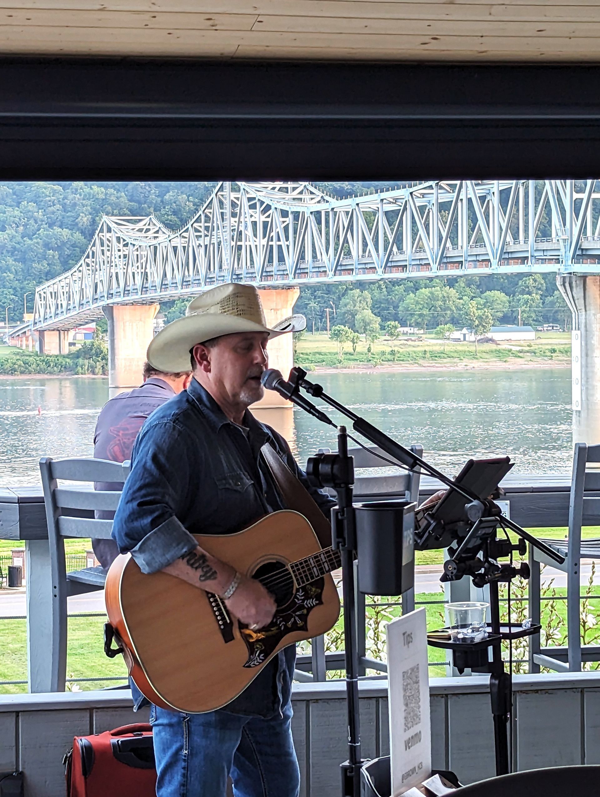 A man in a cowboy hat is playing a guitar and singing into a microphone.