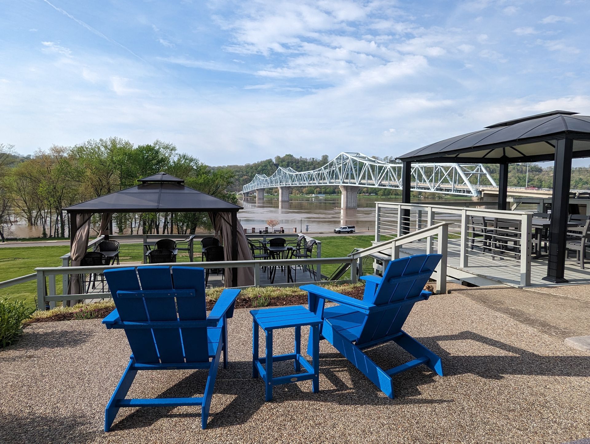 A couple of blue chairs sitting on top of a gravel patio next to a gazebo.