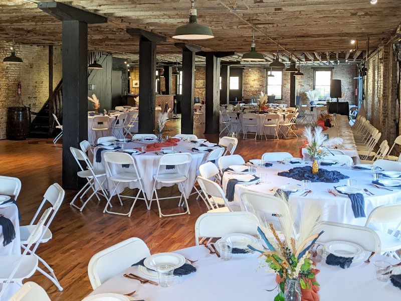 A large room with tables and chairs set up for a wedding reception.