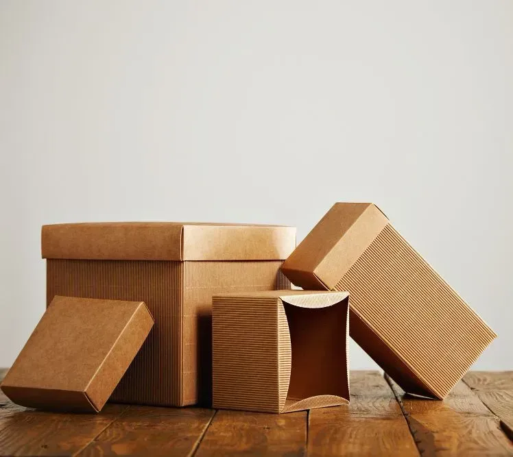 Cajas de cartón de diferentes tamaños y formas sobre una superficie de madera sobre un fondo blanco liso.