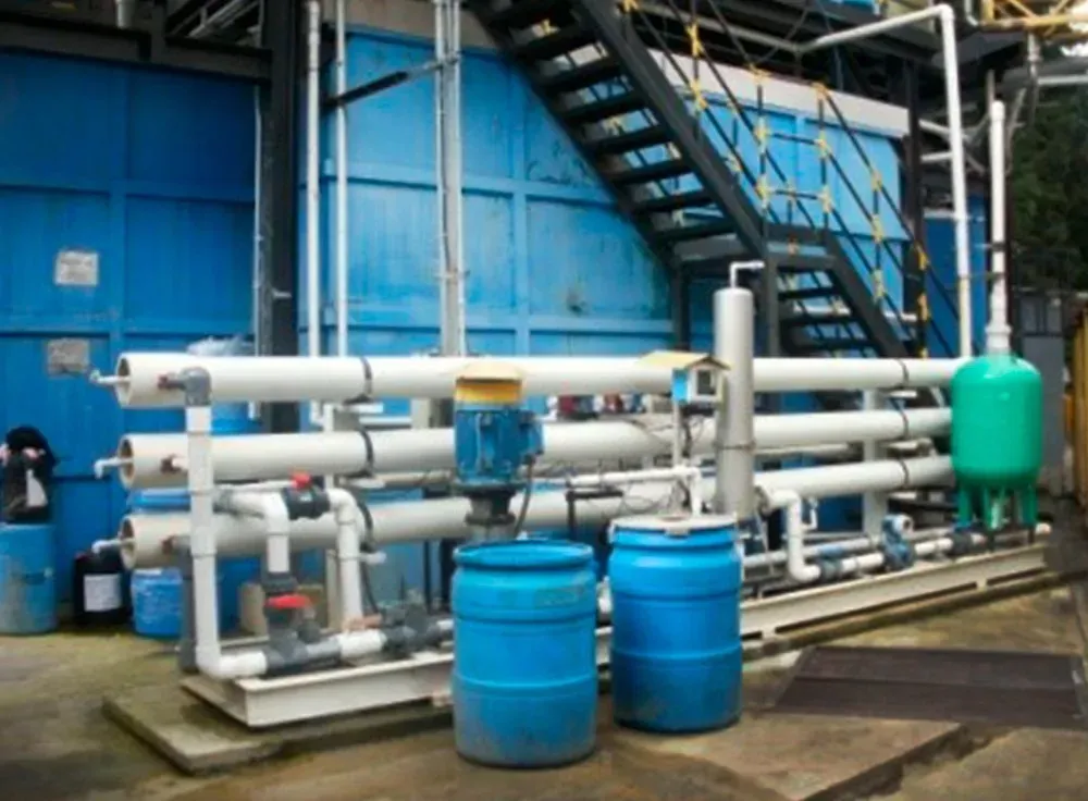 Sistema de filtración de agua industrial azul con tuberías, tanques y escaleras.