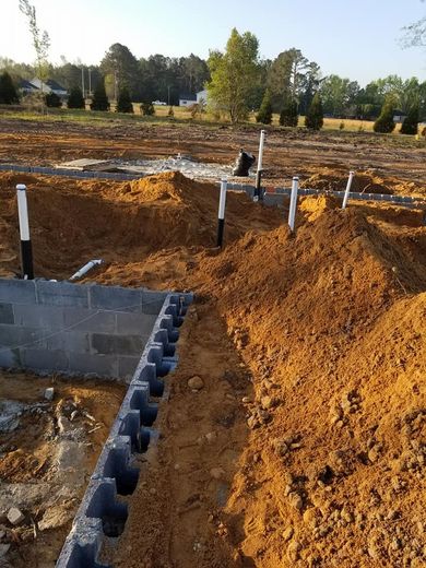 A pile of dirt is sitting next to a brick wall.