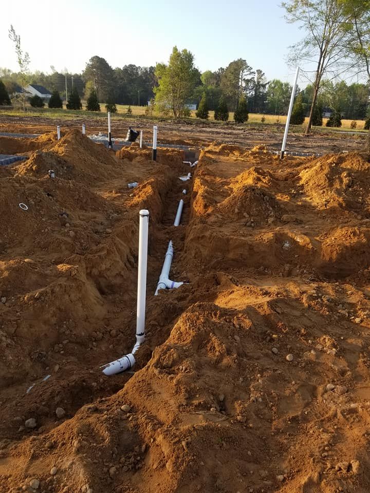 A bunch of pipes are laying in the dirt.