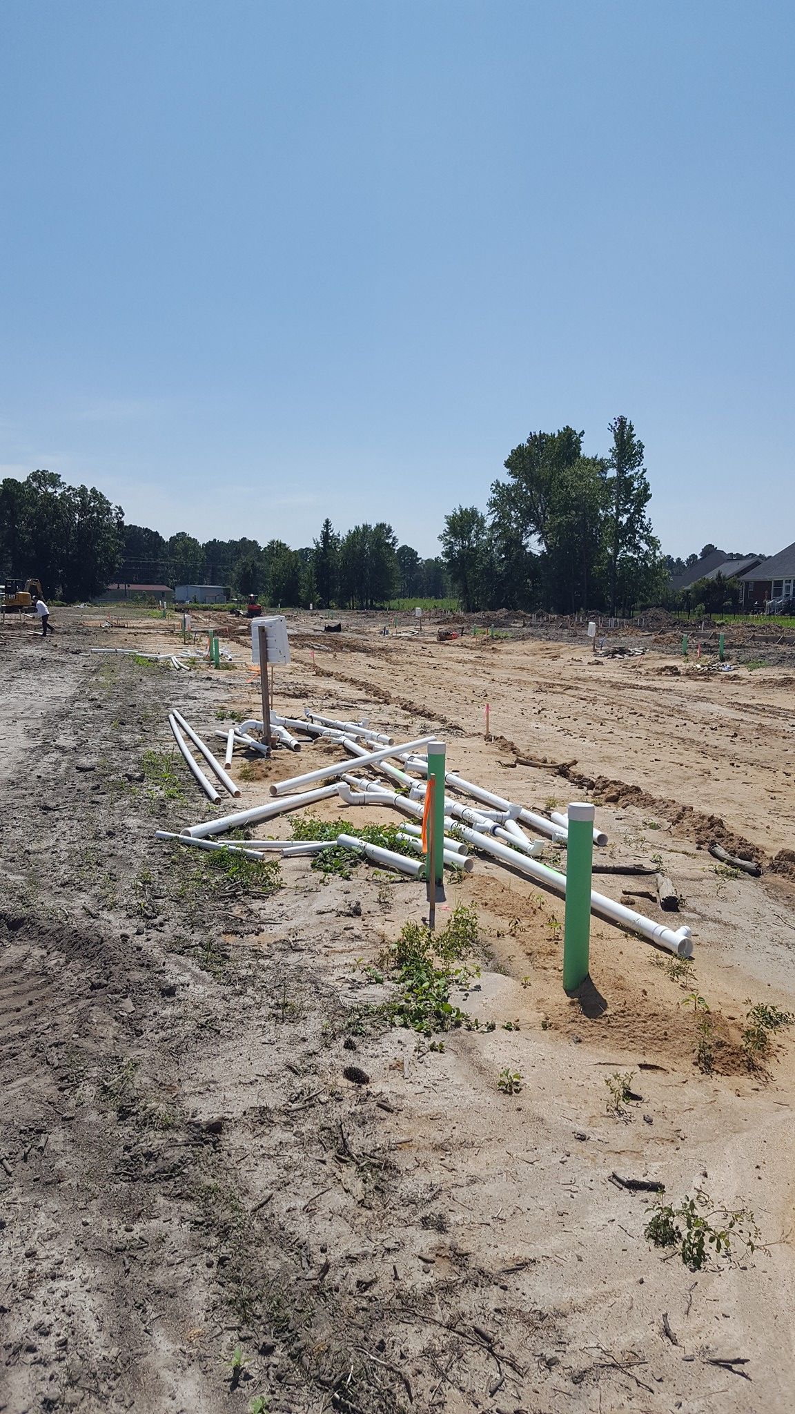 A bunch of pipes are laying on the ground in a dirt field.
