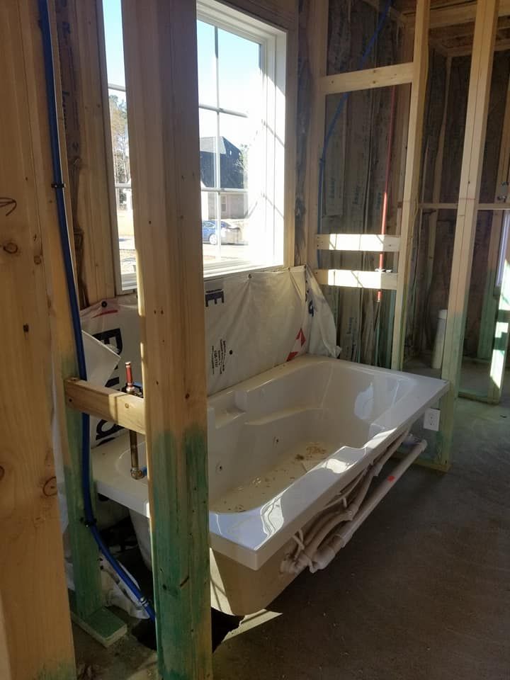 A bathtub is sitting in the middle of a room under construction.