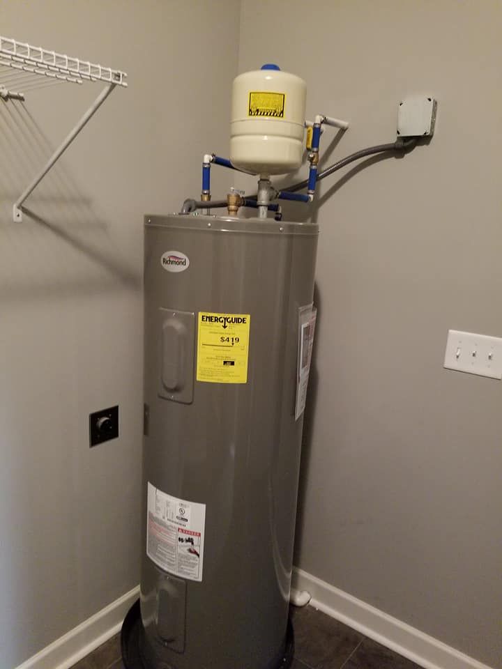 A gray water heater is sitting in a corner of a room.