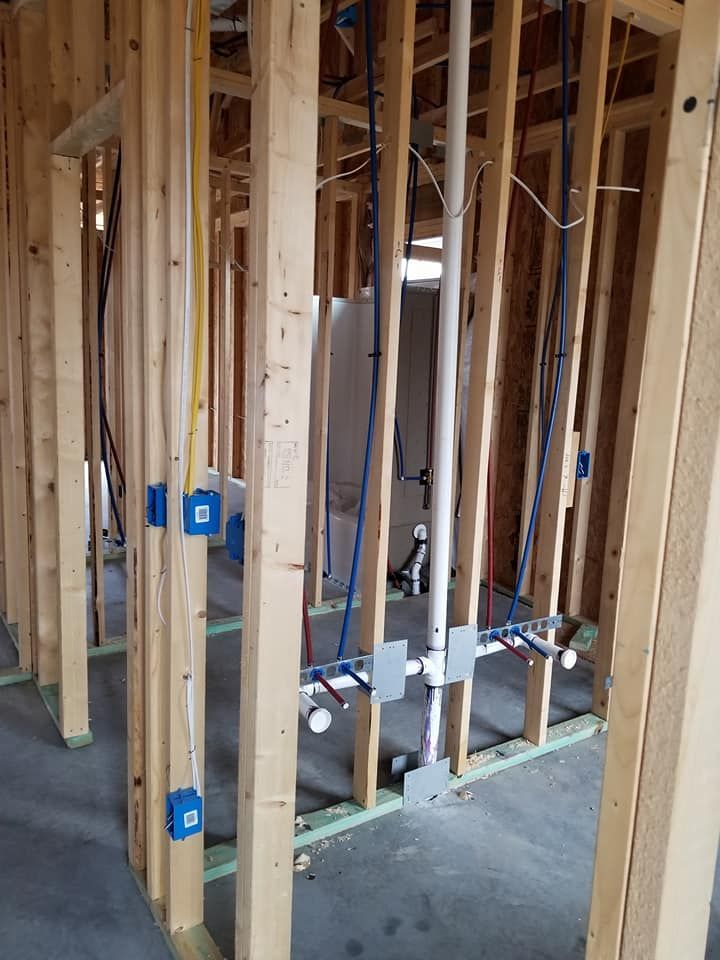 A house is being built with wooden beams and pipes hanging from the ceiling.