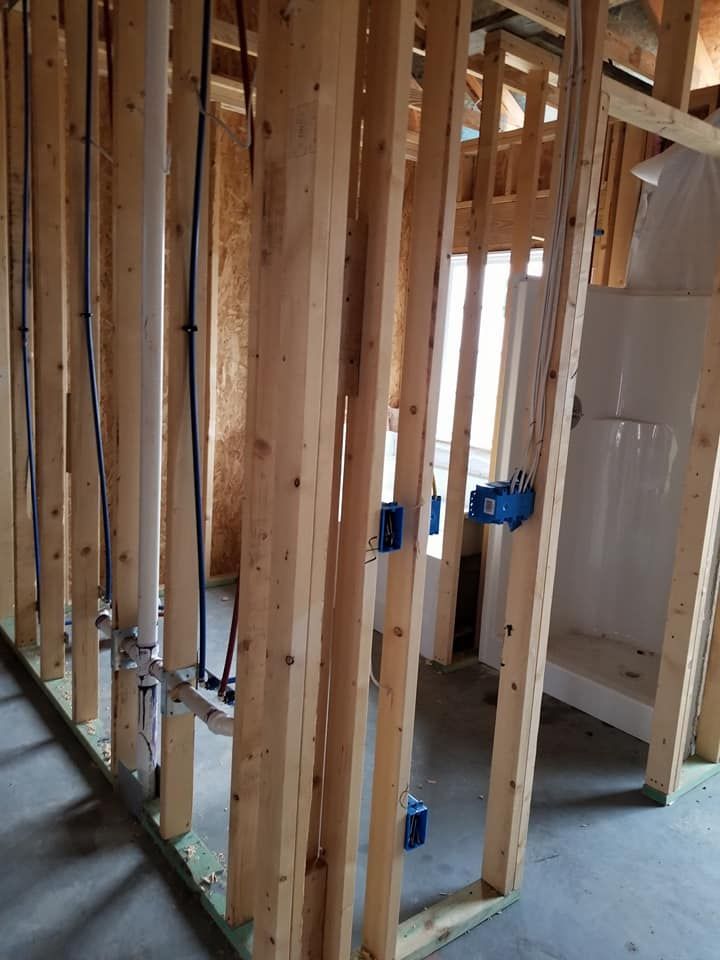 A room in a house under construction with wooden beams and pipes.