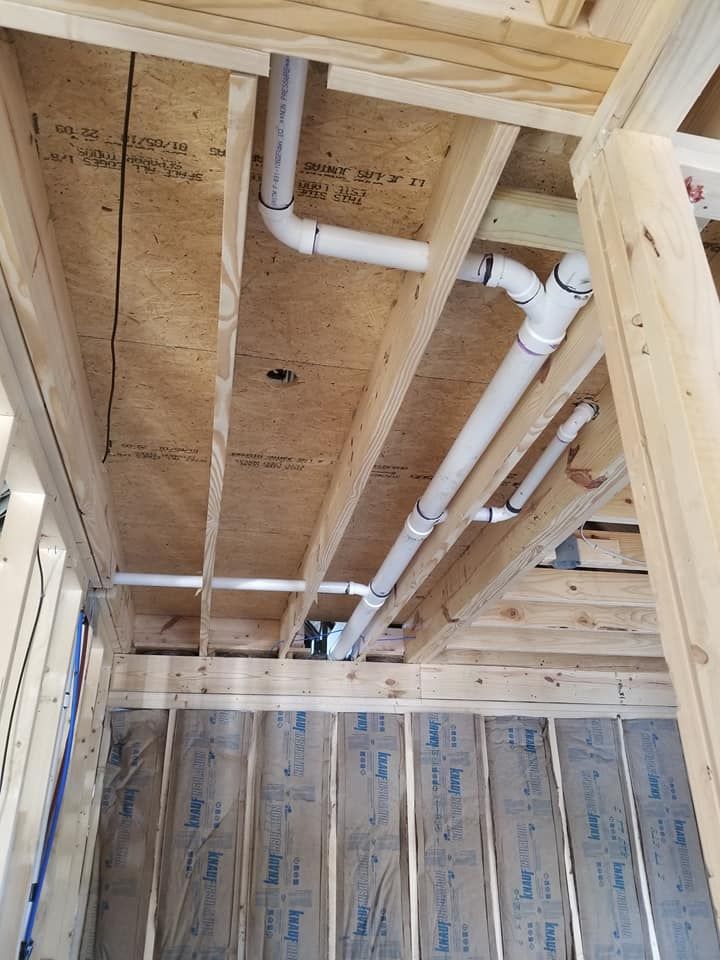 A room under construction with pipes coming out of the ceiling.