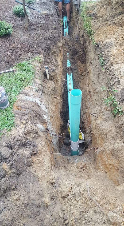 A blue pipe is being installed in a trench.