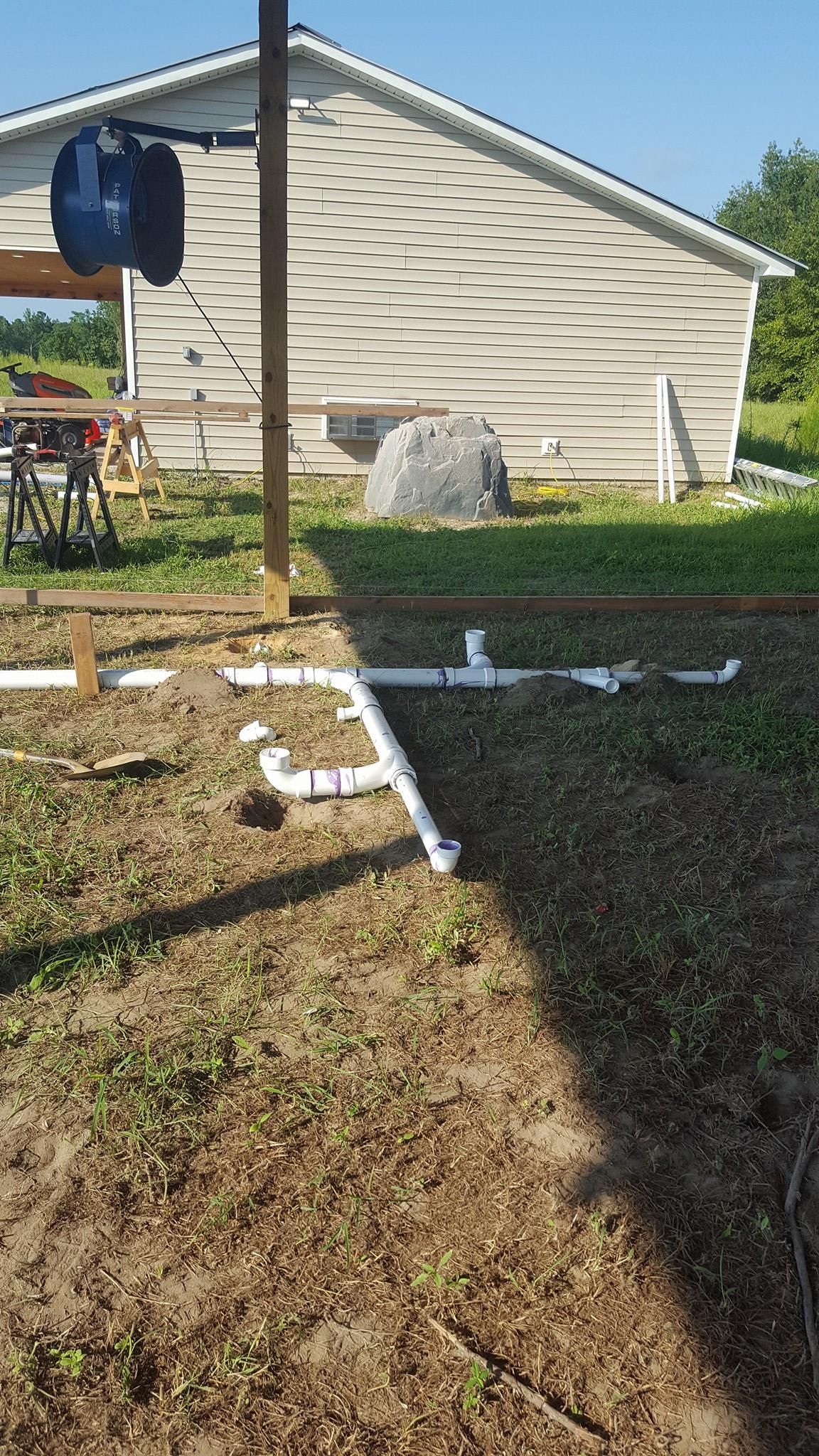 There is a house in the background and a lot of pipes in the ground.