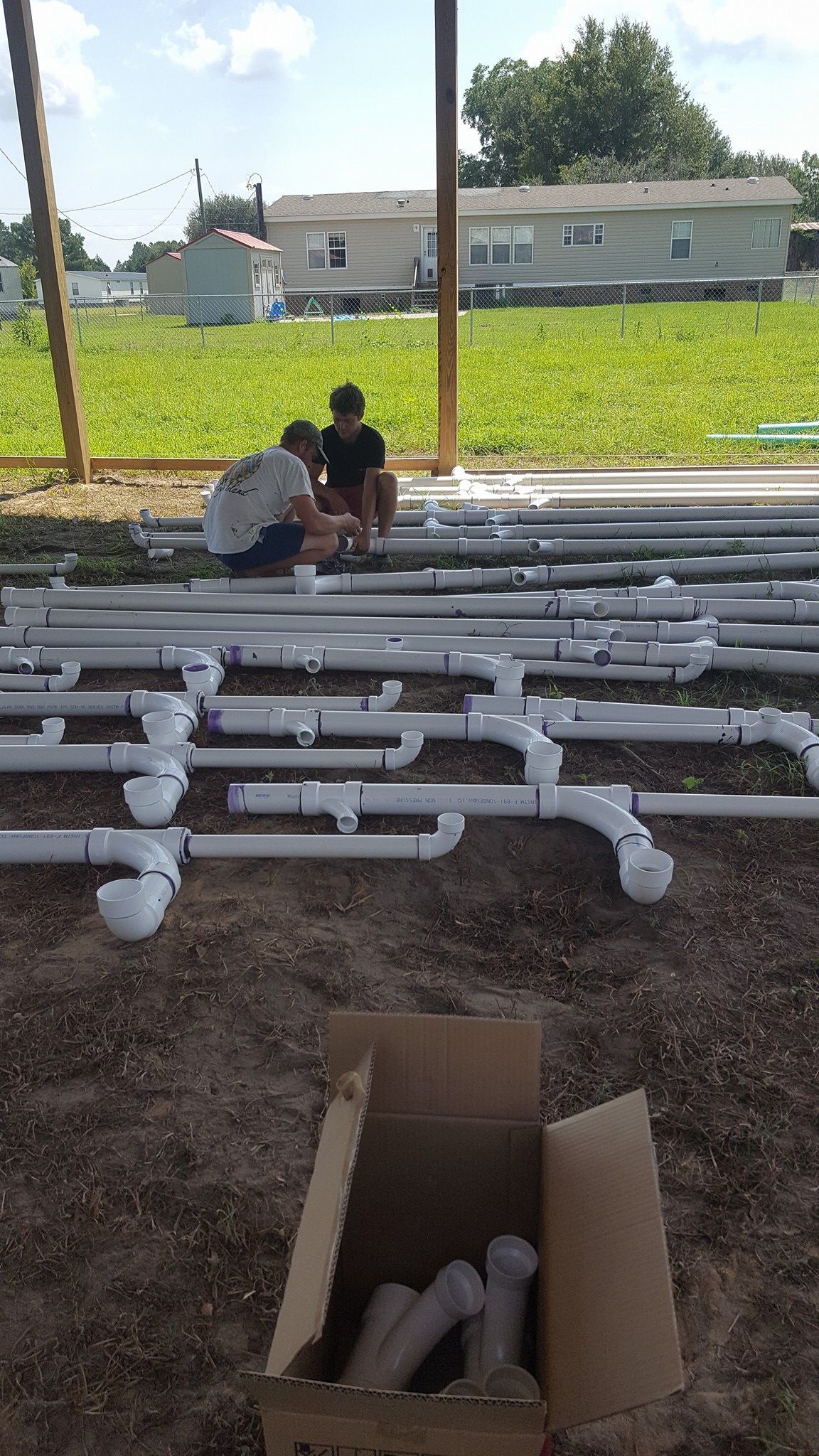 Two men are sitting on top of a pile of pvc pipes.