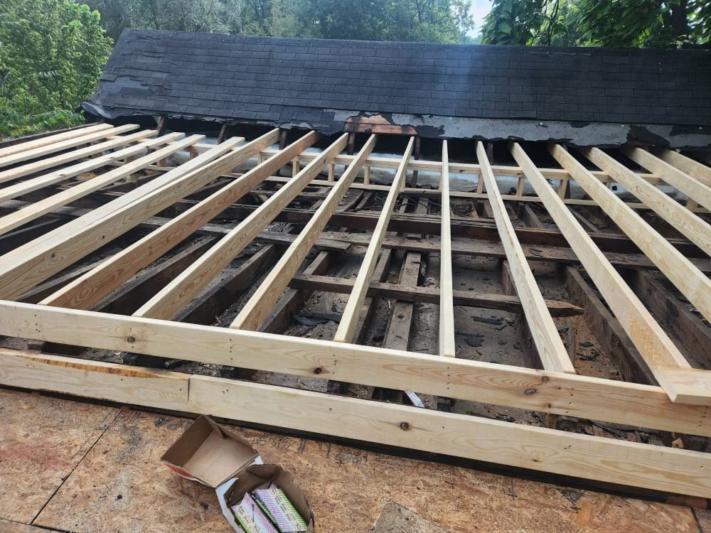 A view of a roof under construction with new wooden joists installed over older, dark timber rafters.