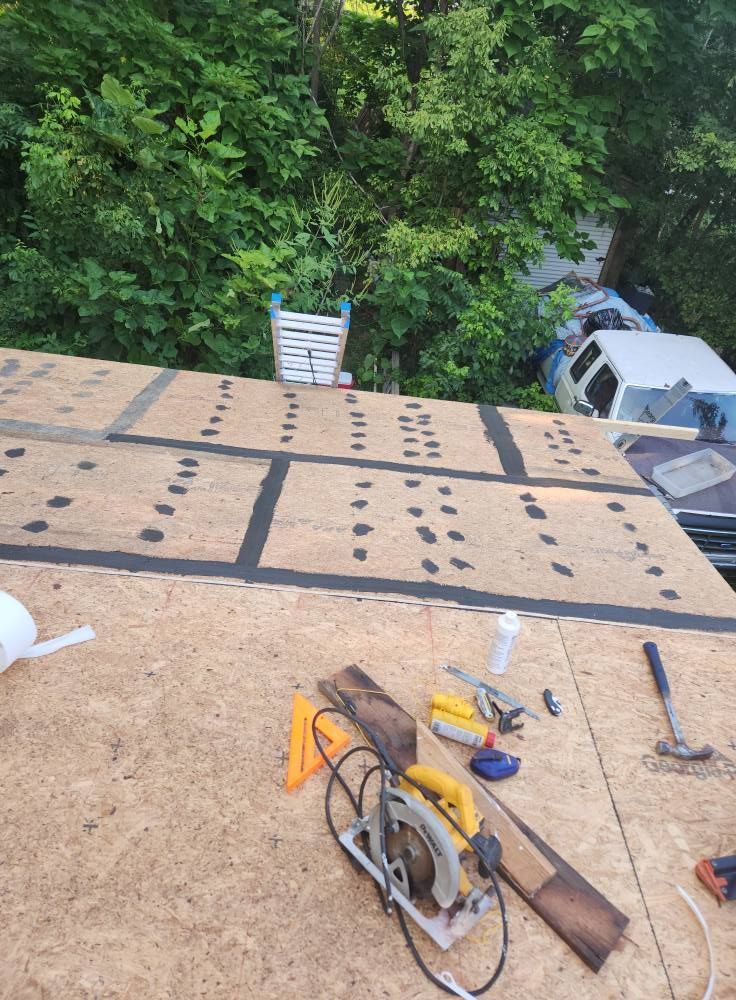 OSB roof sheathing installed with black sealant strips, featuring a circular saw and various construction tools nearby.