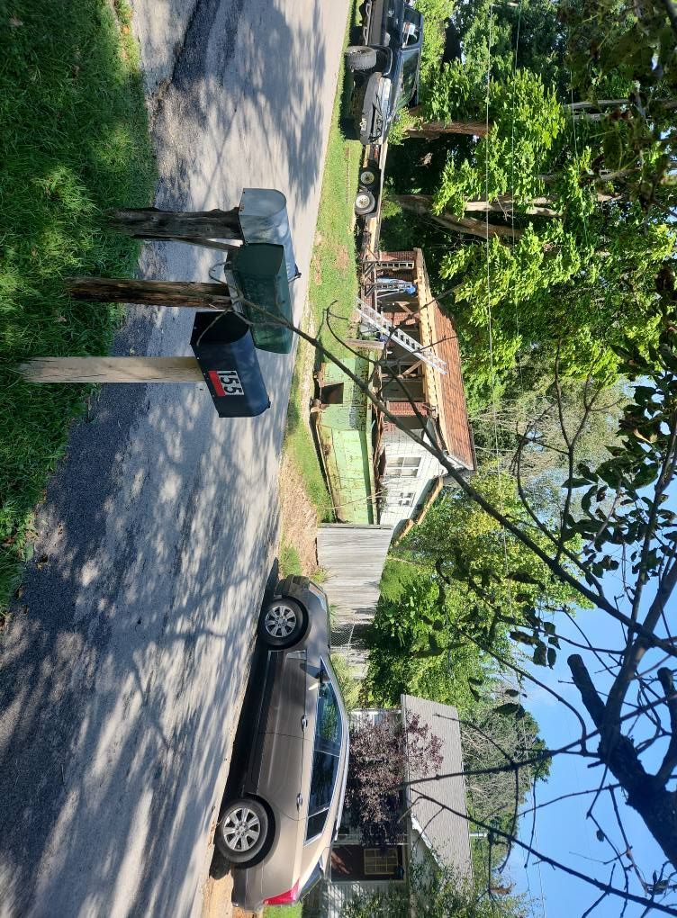 A street-level view of a residential driveway with a silver car, two mailboxes on posts, and a house in the background.