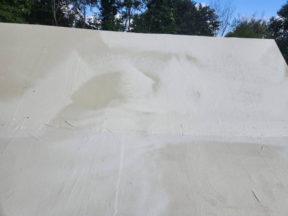 Close-up of a weathered, light-colored tent canopy showing patches, creases, and discoloration under a sunny sky.