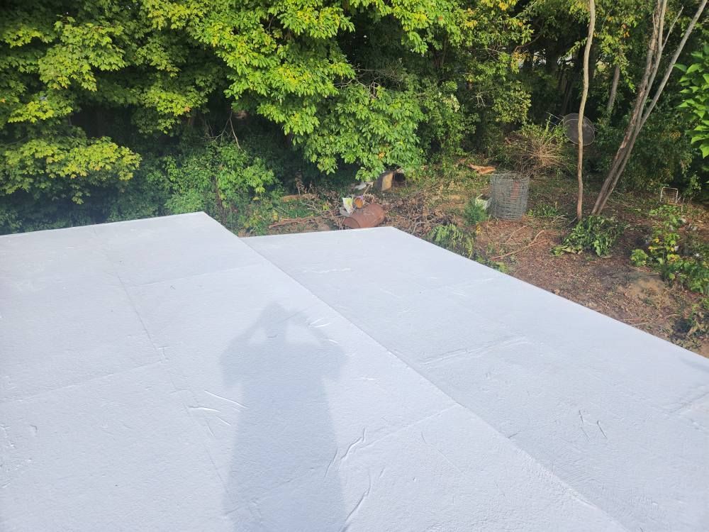 A high-angle view of two light grey, tiered outdoor platforms set against a backdrop of green trees and bushes.