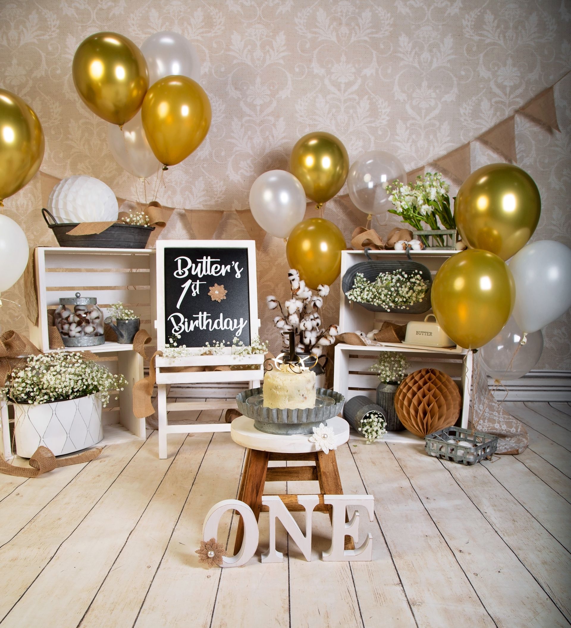 A wooden floor with balloons and a sign that says ONE.