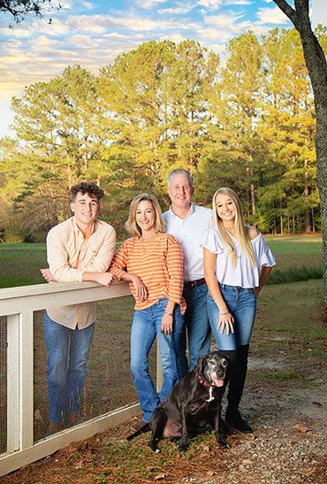 A family is posing outside for a picture with their dog.