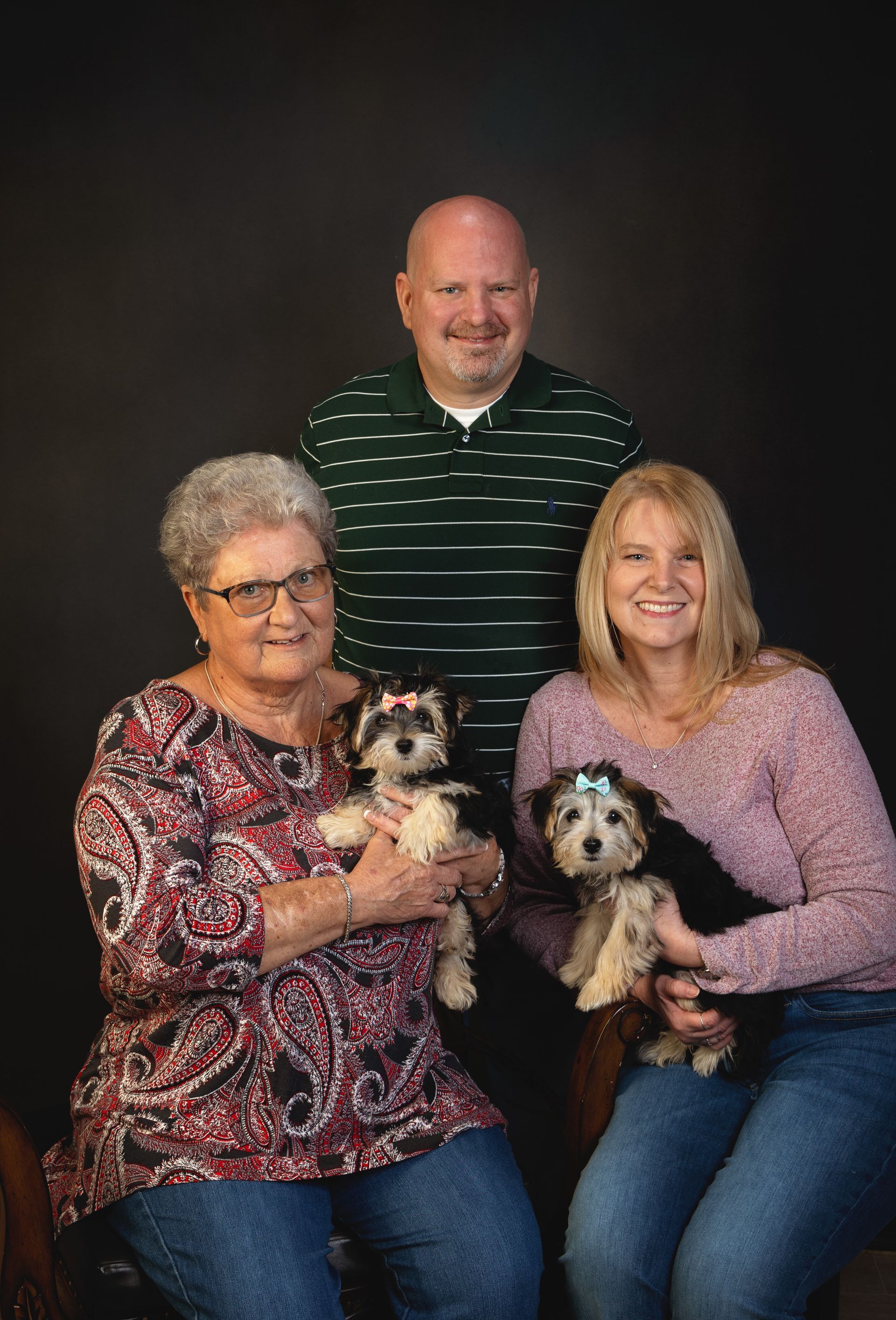 Three adults posing for a picture with two dogs.