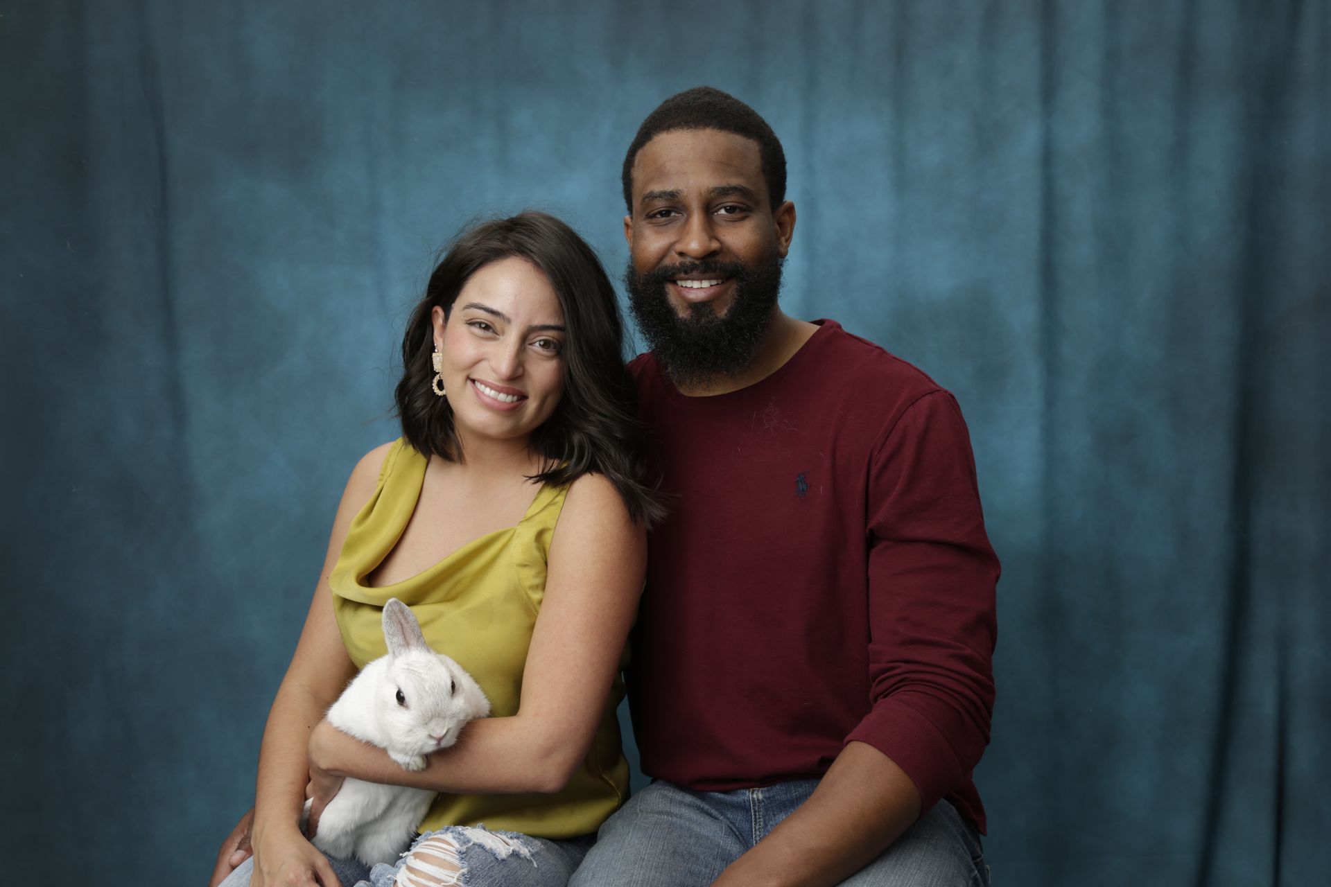 A man and a woman are posing for a picture with a bunny rabbit.