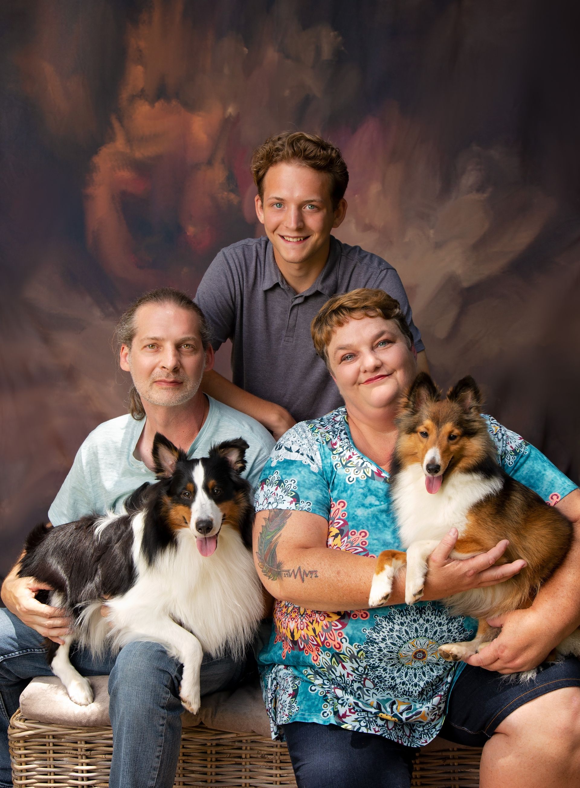 A family is posing for a portrait with their dogs.