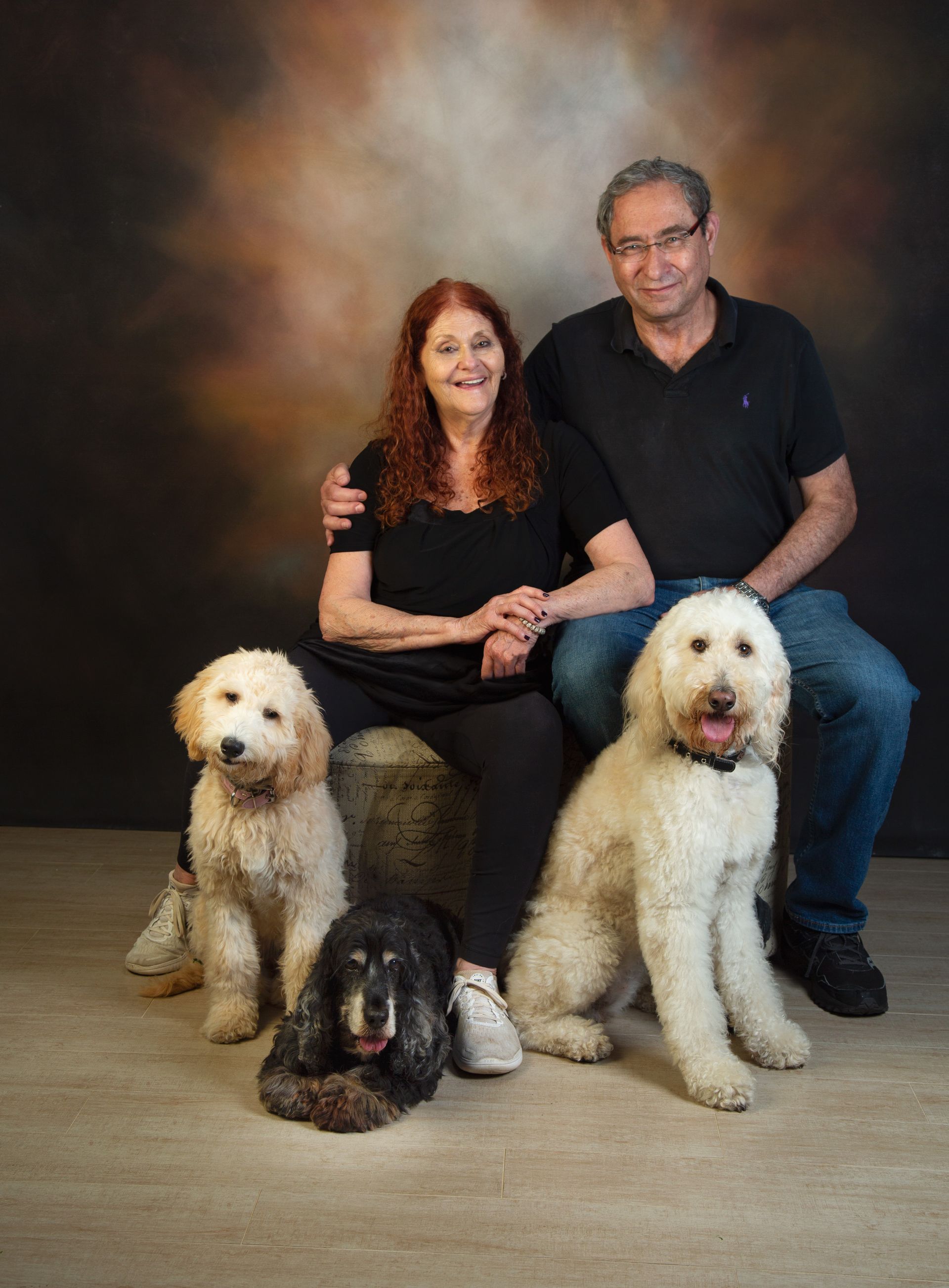 A man and a woman are posing for a picture with their dogs.