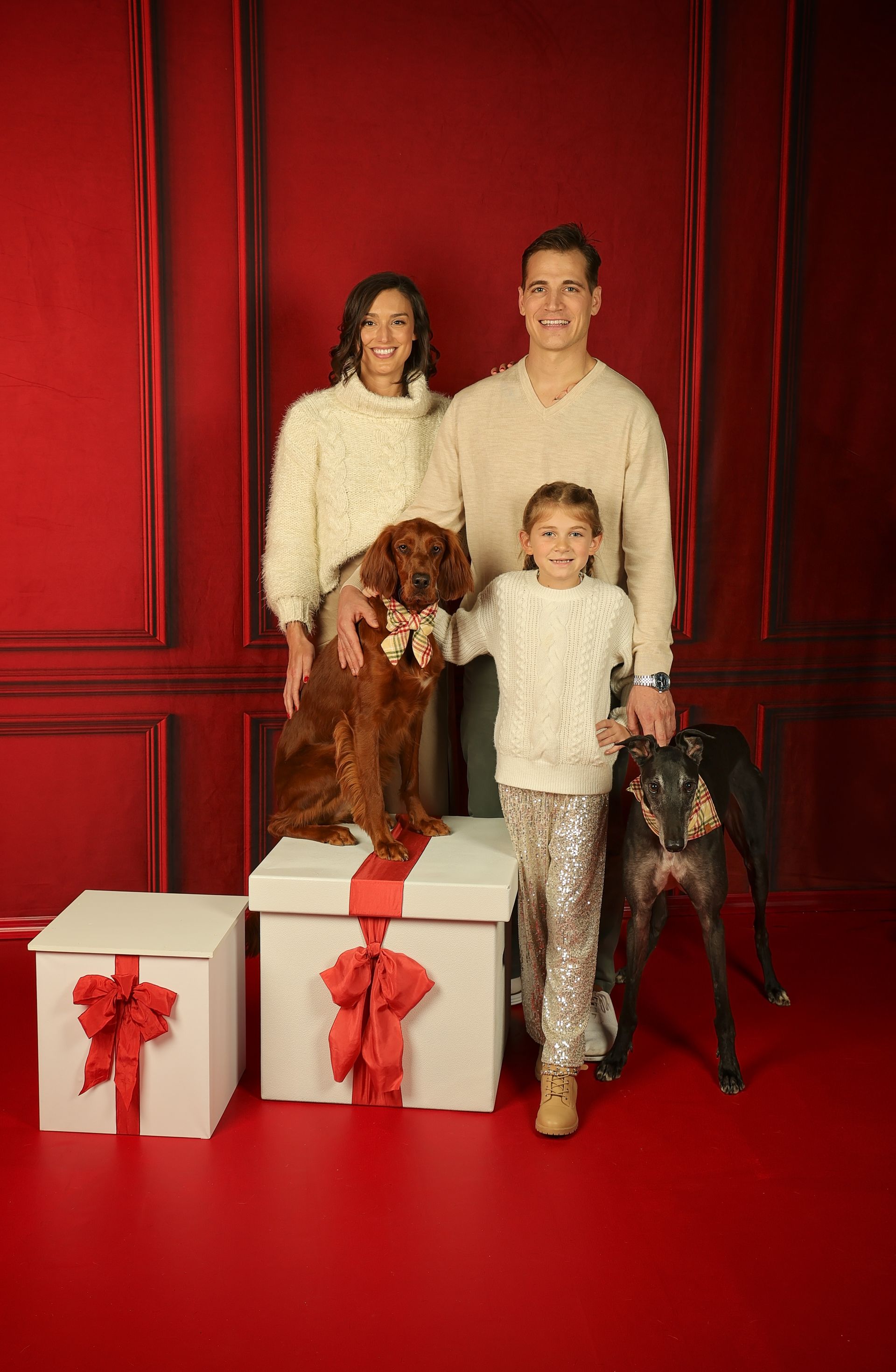 a family is posing for a picture with their dogs and gifts .