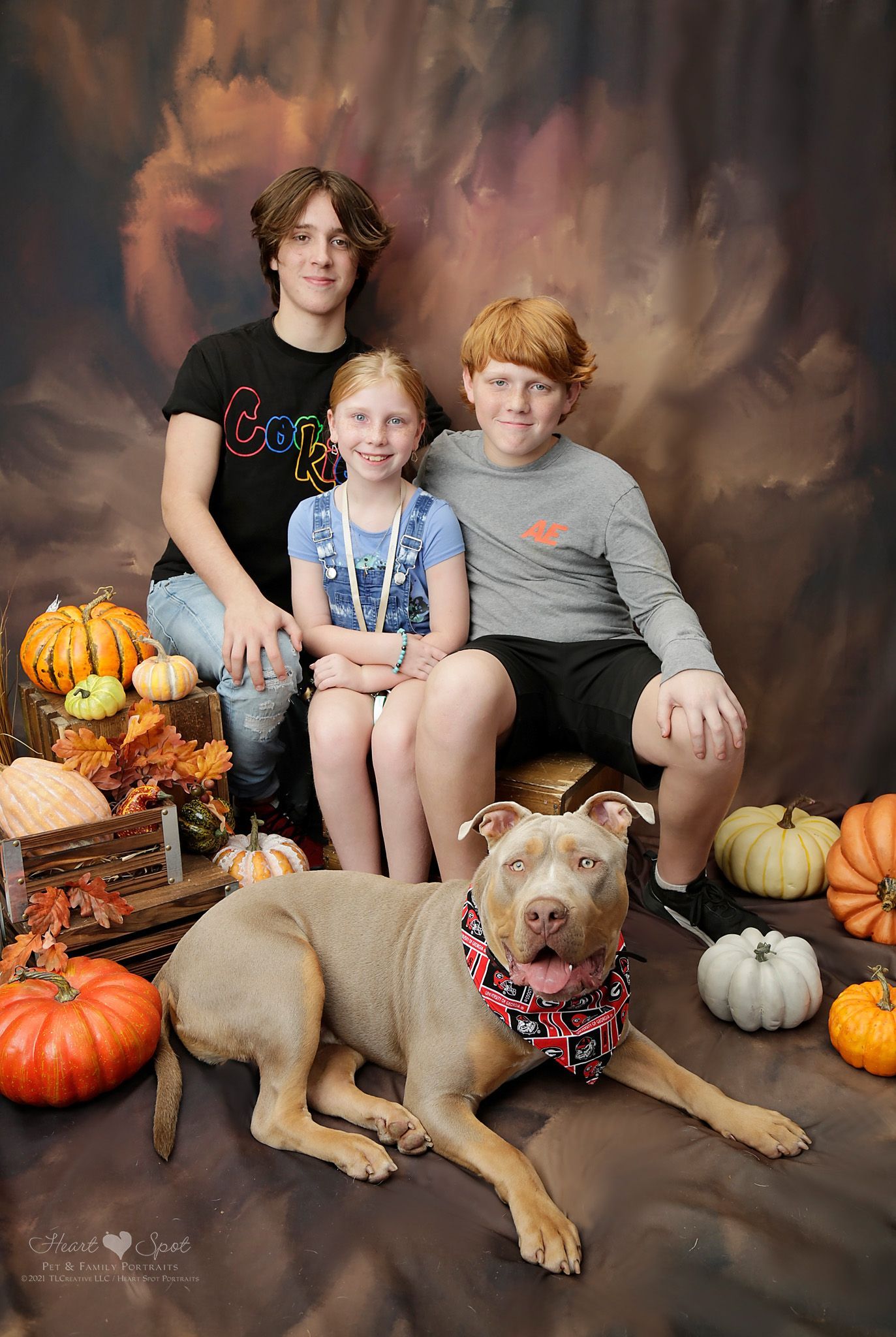 Two boys and a girl are posing for a picture with a dog.