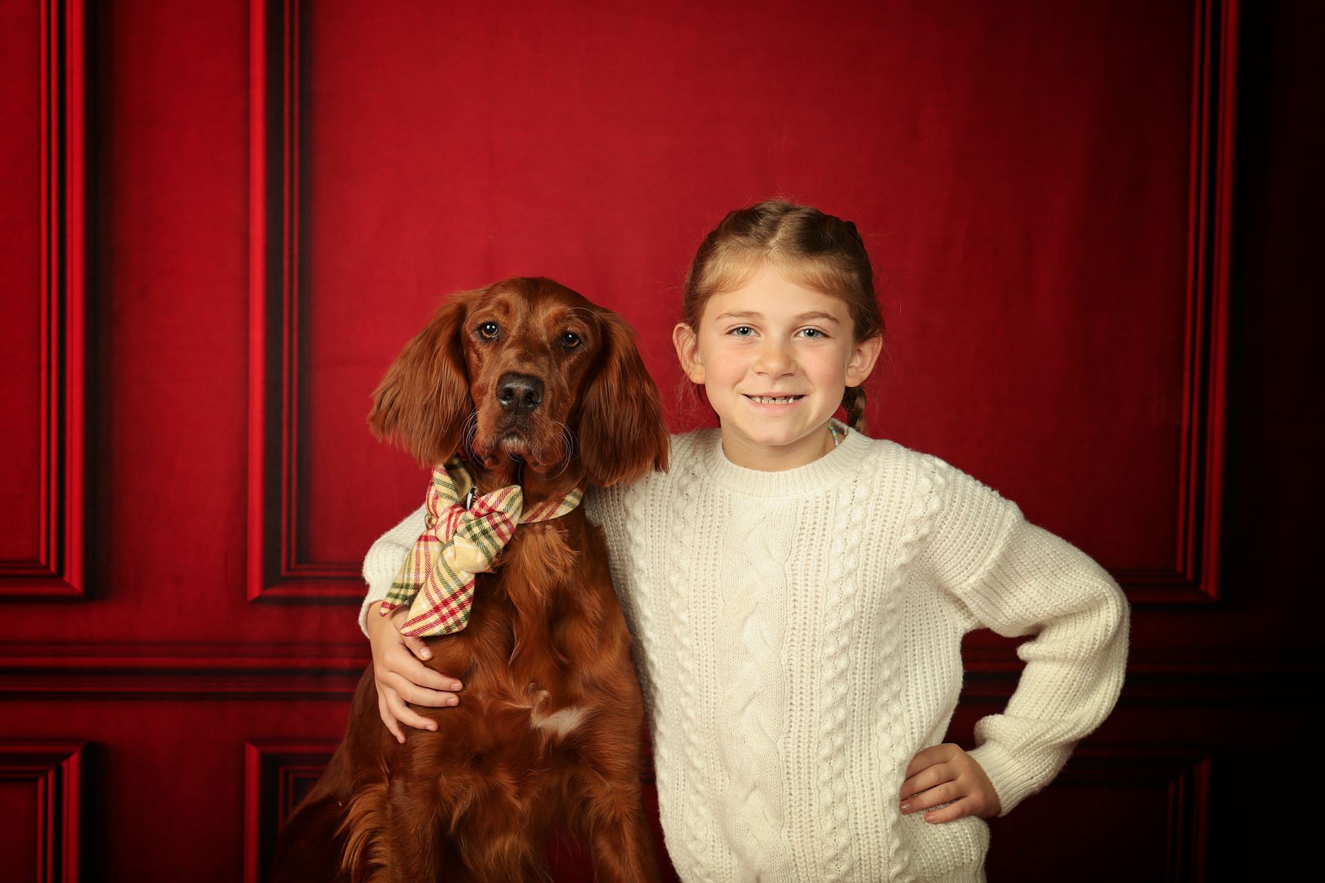 A little girl is posing for a picture with her arm around her dog.