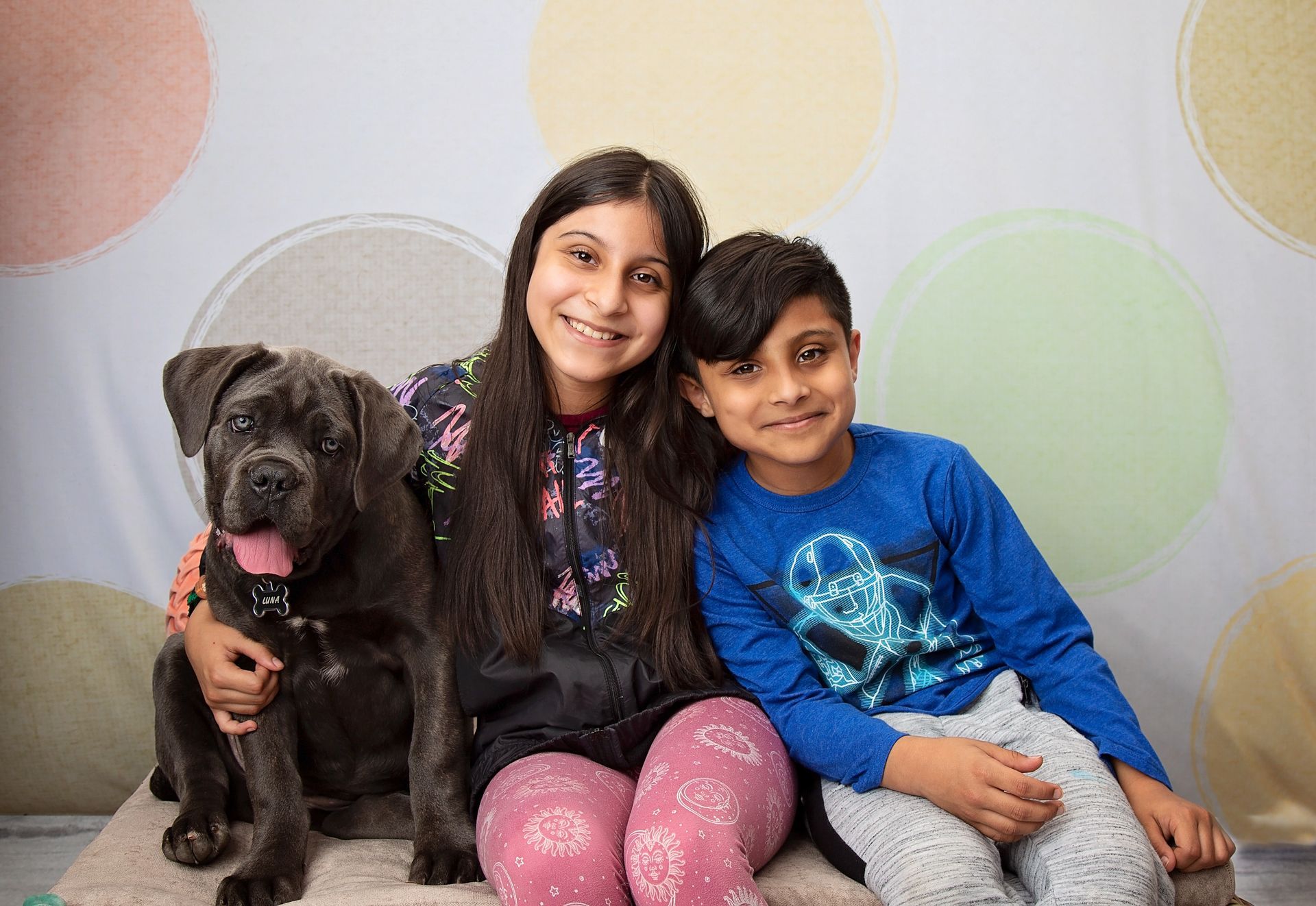 A girl and a boy are posing for a picture with a dog.