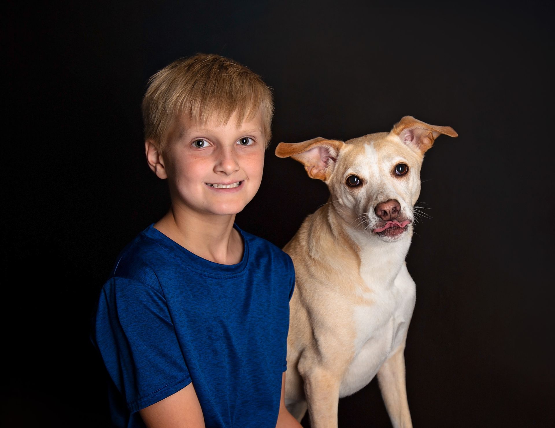 A young boy is posing for a picture with his dog.
