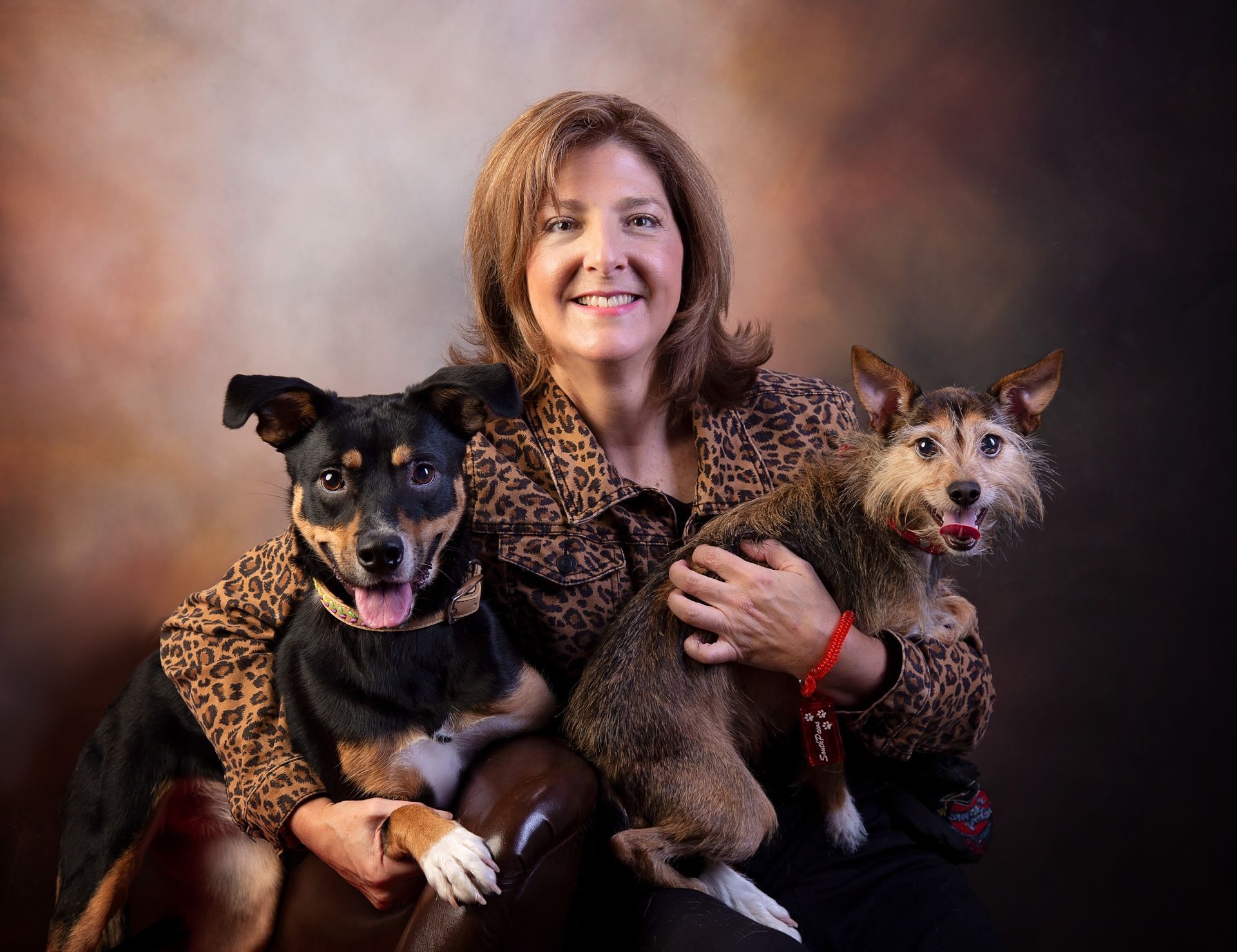 A woman is holding two dogs wearing matching outfits.