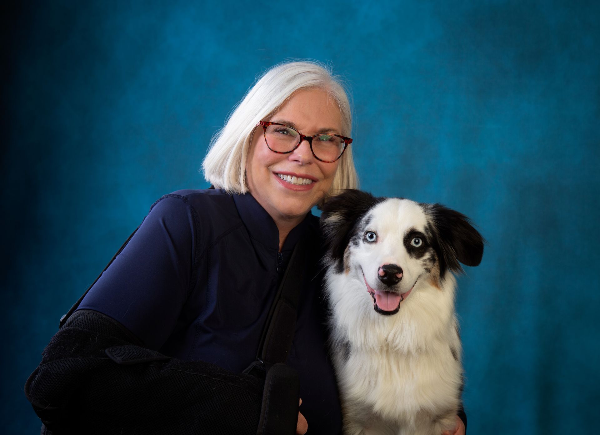 A smiling woman is holding a happy black and white dog in her arms.