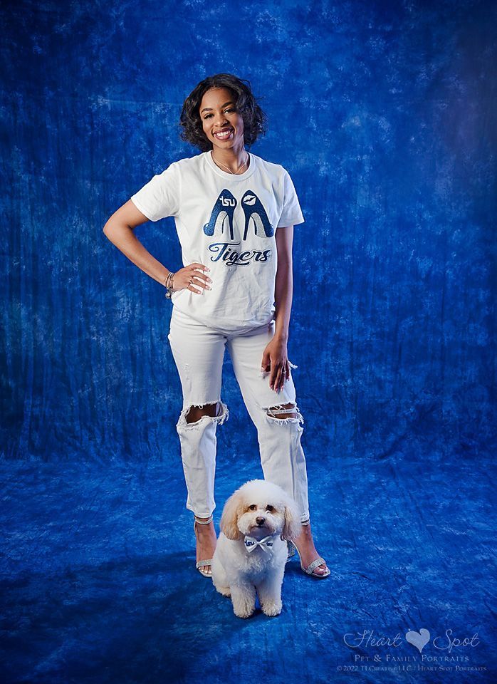 A woman in a white shirt is standing next to a small white dog.