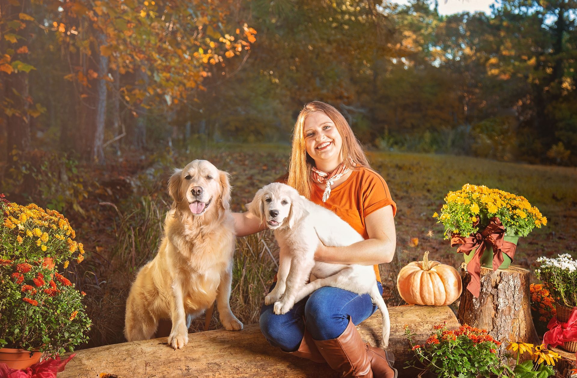 A woman is sitting on a hay bale with two dogs.