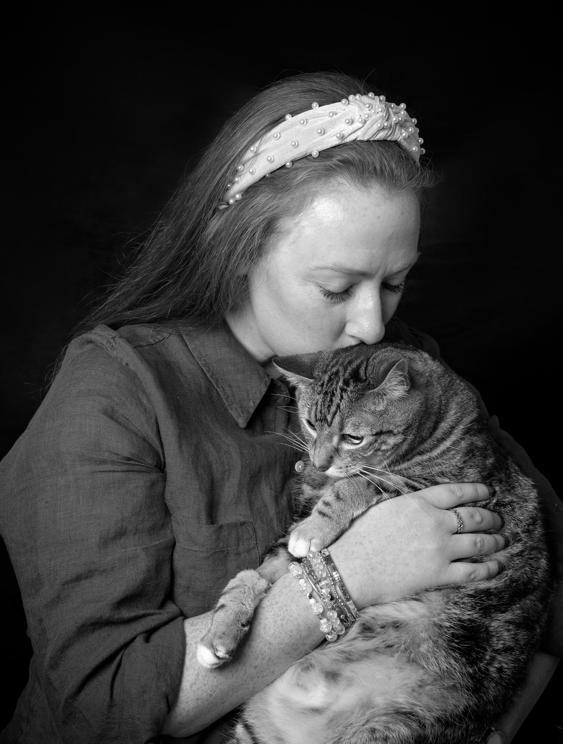 A woman is holding a cat in her arms in a black and white photo.