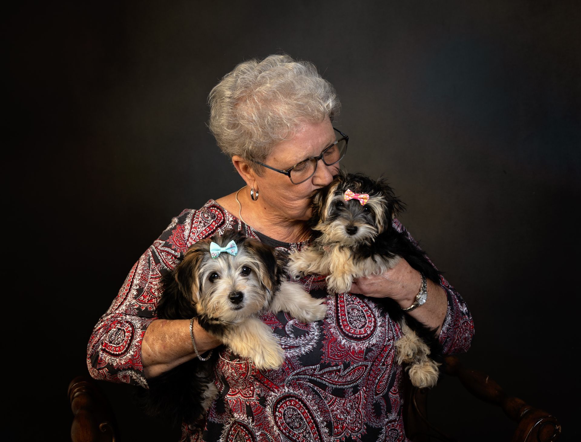 An elderly woman is holding two small dogs in her arms.