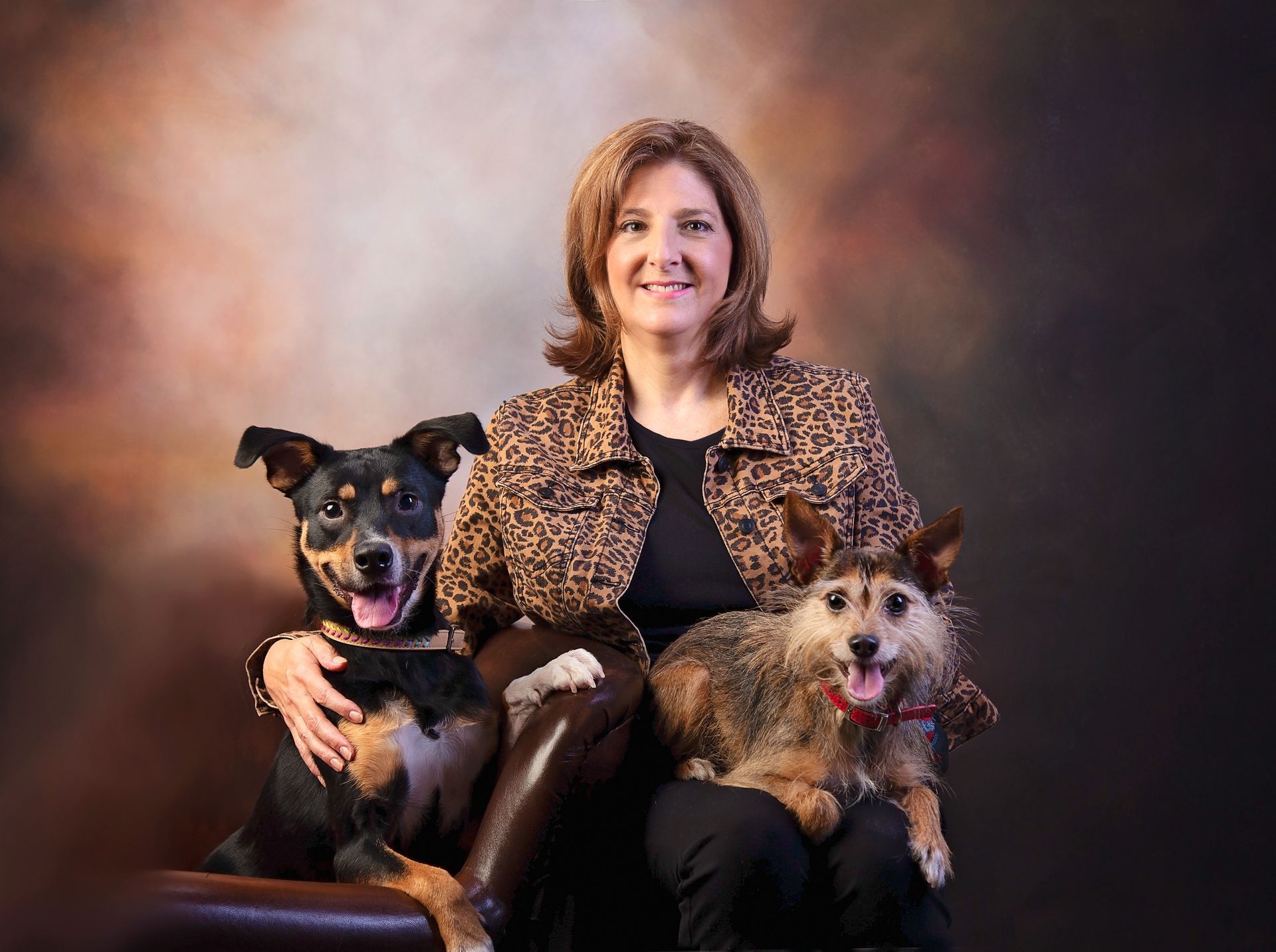 A woman is sitting on a couch with two dogs.