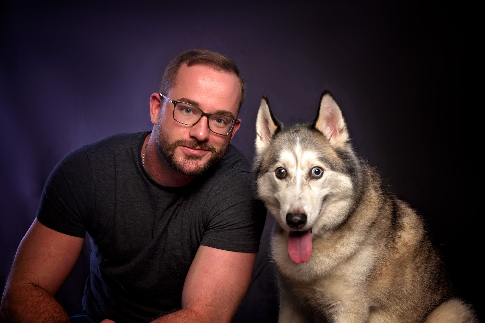 A man and a husky dog are posing for a picture.