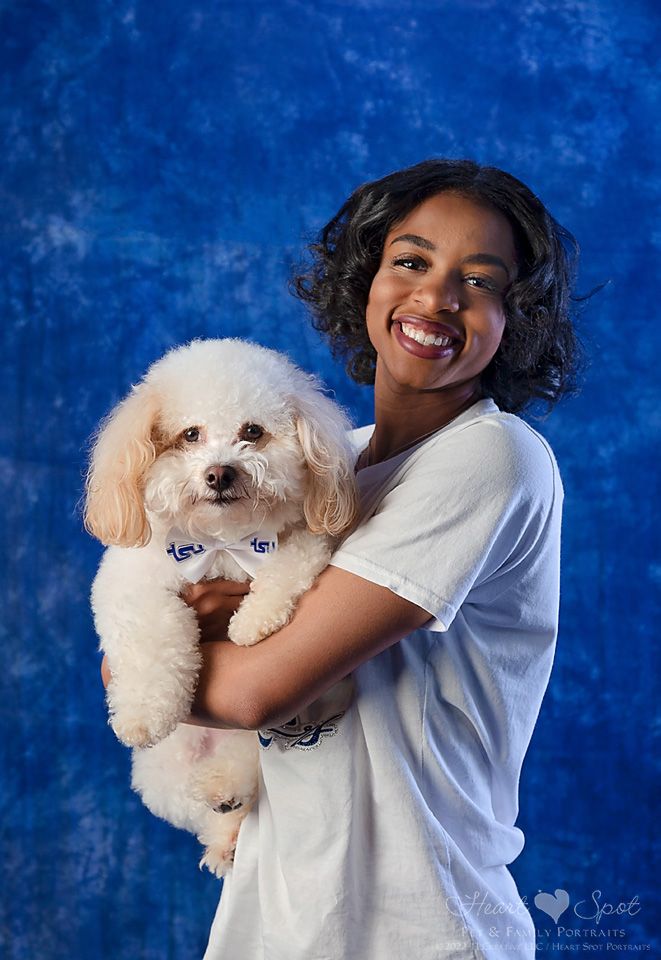 A woman is holding a small white poodle in her arms.
