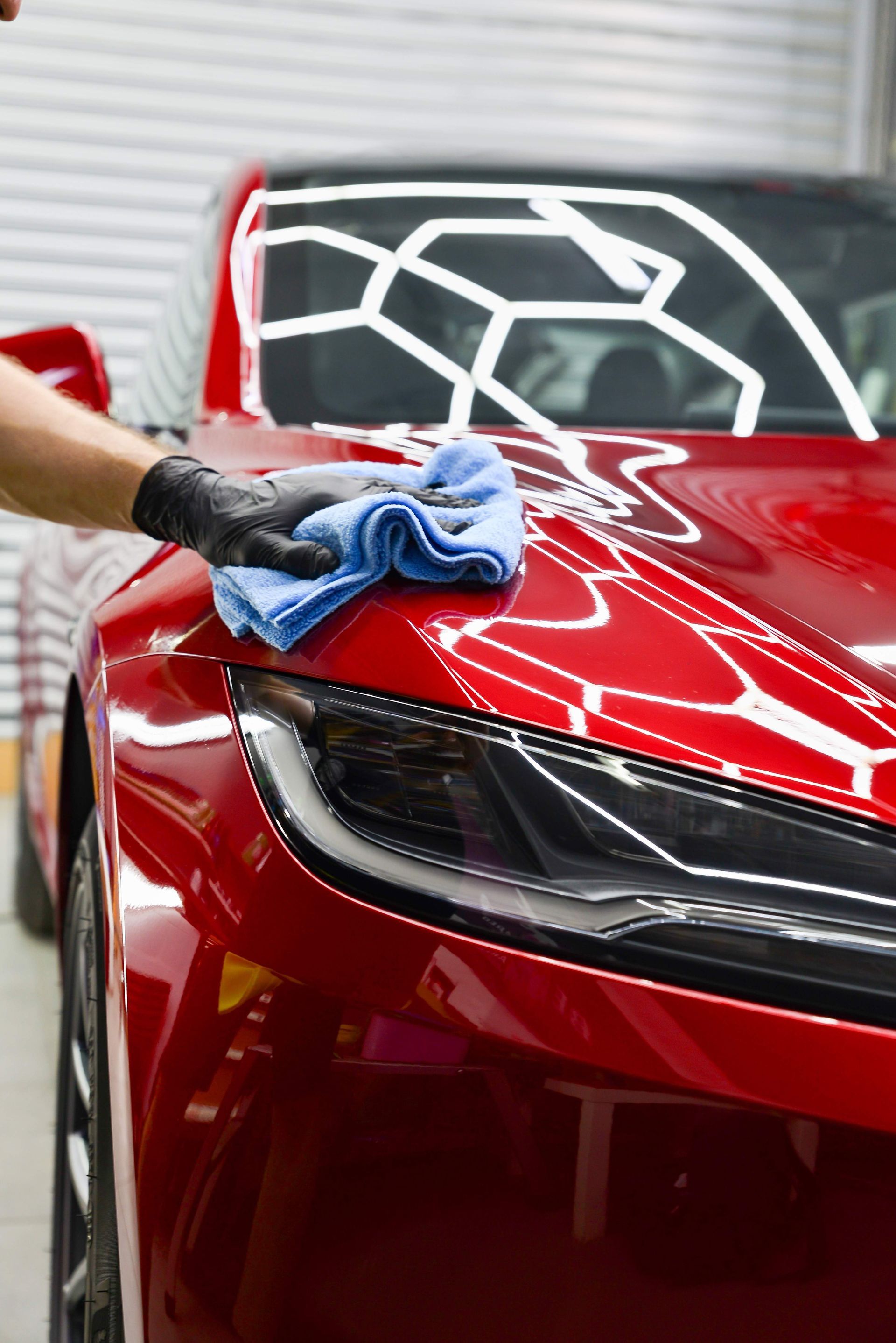 A person is cleaning a red car with a blue cloth.