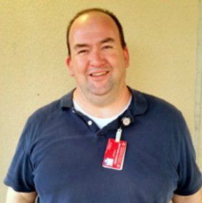 A man wearing a blue shirt has a name tag on his neck